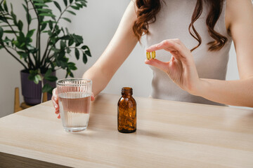 A woman holds omega-3 fish oil capsules. Healthy lifestyle, prevention and treatment of diseases. The woman takes and drinks dietary supplements and vitamins for skin, nails and hair. 