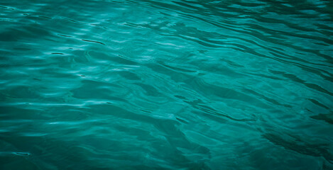 Blue and green background showing reflection of light on the wavy surface of the water