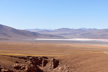 Vast landscape of Avaroa National Park in Bolivia showcases arid mountains and expansive salt flats under clear blue skies