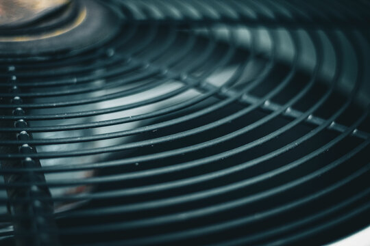 the fan guard or grille with blade before on an outdoor air conditioning unit. hvac, energy efficiency, or heat wave background. business or industry design element