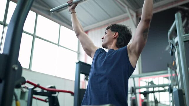 Young sportsman strengthens back muscles with lat pulldown exercise
