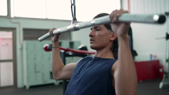 Young sportsman strengthens back muscles with lat pulldown exercise