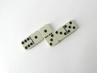 Three dominoes lying on clean white background, minimalist composition, strategic game pieces, soft...
