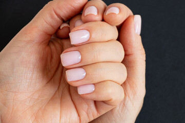 Women's hands with a delicate light manicure on a black background, hand