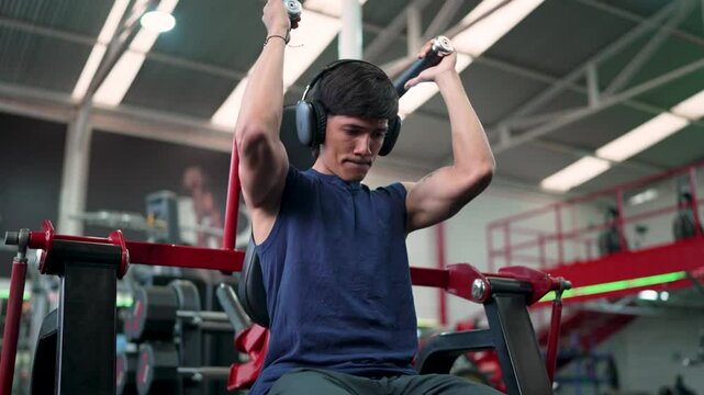 Determined male athlete performing abs pulldowns, strengthening abs muscles in gym