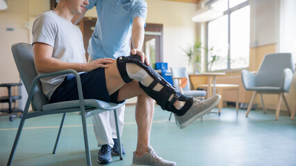 Man in rehabilitation with leg brace assisted by physiotherapist – injury recovery, physical therapy, and orthopedic treatment