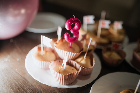 3rd birthday celebration with cupcakes and a pink candle surrounded by family and friends