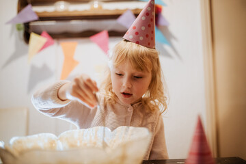 Sibling enjoying a fun birthday celebration while making a cake at home with colorful decorations