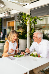 Happy senior couple enjoying a healthy lunch with wine at an outdoor restaurant