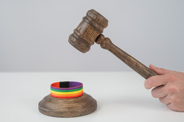 Judge hits gavel on rainbow bracelet. 