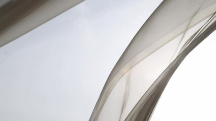 Light breezy sheer curtain blowing in the wind with garden behind it