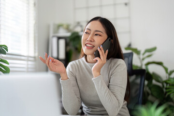 Communication and Connection. Young woman talking on phone in a modern home office.