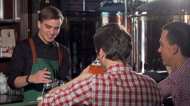 Charming bartender serving refreshing craft beer to delighted customers