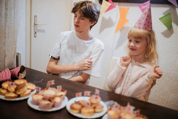 Celebrating sibling bond during a joyful birthday gathering with cupcakes and decorations