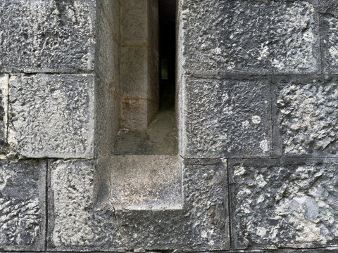 Stone Wall Arrow Slit: An up close view of an arrow slit in a weathered stone wall highlighting texture and architecture