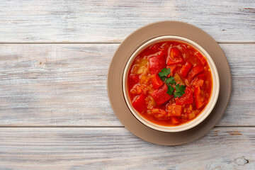 Traditional Hungarian dish lecho or Lecso or Letscho. Stew with peppers, tomatoes and onions in bowl on wooden background.