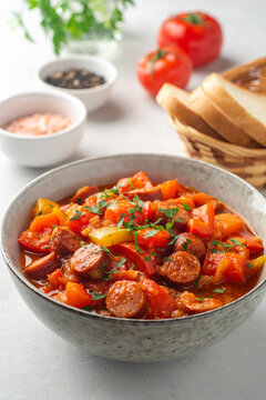Traditional Hungarian dish Lecho or Lecso or Letscho. Stew with peppers, tomatoes, onions and sausages in bowl on concrete background.