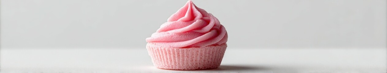 Delicious pink frosting cupcake on a clean white surface in natural light