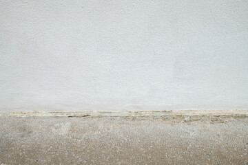 Concrete floor meets the base of a textured white wall Neutral colors provide a simple minimalist...