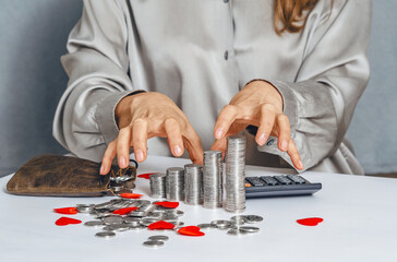 Greedy female hands reaching for silver coins with red heart. Leather bag, calculator. Concept of theft, embezzlement, fraud and greed.