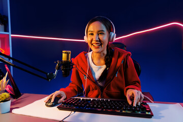 Host channel of smiling beautiful Asian girl streamer playing online game wearing headphone talking...