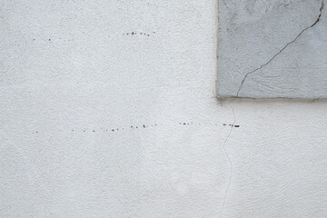 Cracked Stucco Wall: Close up of a textured white stucco wall with cracks and a gray concrete...