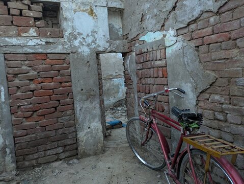 a dilapidated brick interior with a weathered, decaying wall, a red bicycle leaning against the wall, the image has a gritty, abandoned aesthetic, a sense of neglect and deterioration
