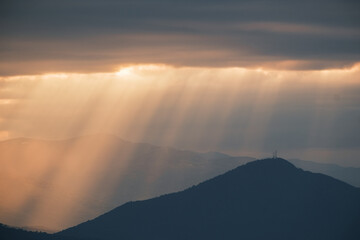 Sunrays break through clouds over hazy mountains silhouetting peaks and adding depth to the landscape Beautiful sunrise at high altitude