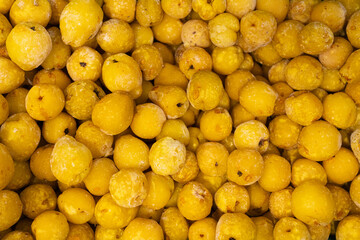 A close-up image showing chopped frozen quinces in various sizes, highlighting their yellow color and icy texture, ideal for culinary use.