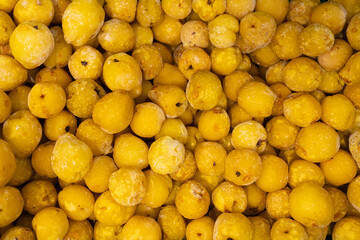 A close-up image showing chopped frozen quinces in various sizes, highlighting their yellow color and icy texture, ideal for culinary use.