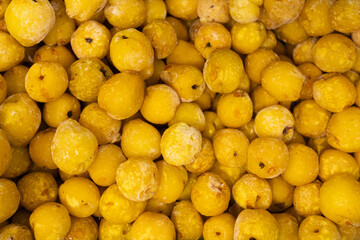 A close-up image showing chopped frozen quinces in various sizes, highlighting their yellow color and icy texture, ideal for culinary use.