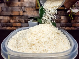 Close up shot of white rice being poured into a clear container