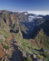 Obraz premium Pico do Arieiro, located in Madeira, Portugal, is home to a mountain trail that offers a thrilling hike, with its rugged terrain, lush green surroundings, and peaks enveloped in clouds, creating an