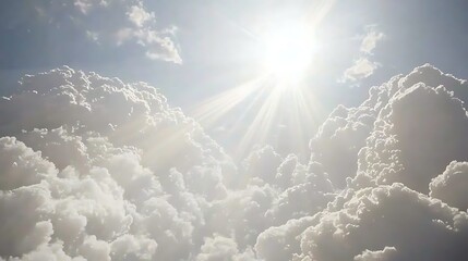 Golden light streaming through fluffy clouds, creating beams of sunlight that break apart the soft blue sky.