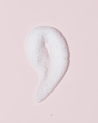 Cosmetic foam smear on pastel pink background, minimal beauty texture
