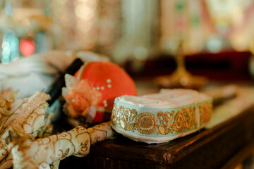 Elegant headwear with intricate gold embroidery. A vibrant orange cap complements the scene. Accessories on a wooden surface, bathed in soft light.
