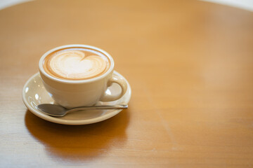 Top  of hot latte coffee with latte art in a white cup on wooden table