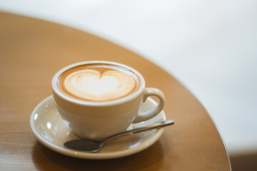 Top  of hot latte coffee with latte art in a white cup on wooden table
