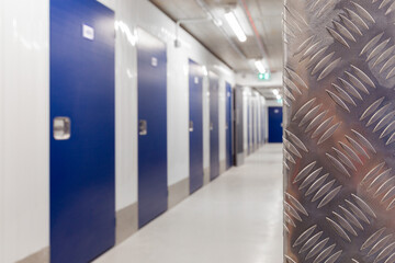 Long hallway within a modern, well-lit self-storage facility with blue doors