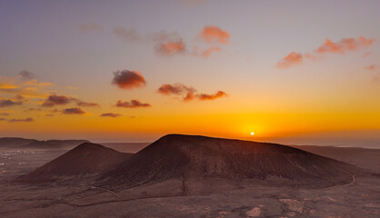 Naklejka premium Spectacular sun set image over Volcan Calderon Hondo volcanic crater silhouetted against the setting sun and skyscape near Corralejo, Fuerteventura, Canary Islands, Spain