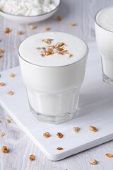 Kefir, buttermilk or yogurt, cottage cheese with granola. Yogurt in glass on white wooden background. Probiotic cold fermented dairy drink. Gut health, fermented products, healthy gut flora conceptt