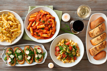 Italian dinner with assorted pasta dishes, bruschetta, garlic bread and glasses of red and white wine on rustic wooden table