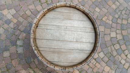 Drewniana beczka widziana z góry postawiona na kolorowym bruku