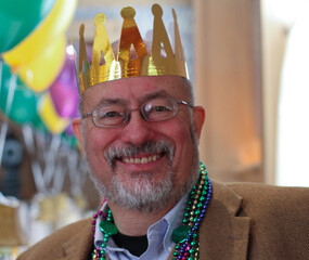 Man in paper crown and mardi gras beads