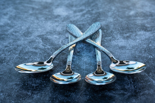 Four silver teaspoons on a dark background. 