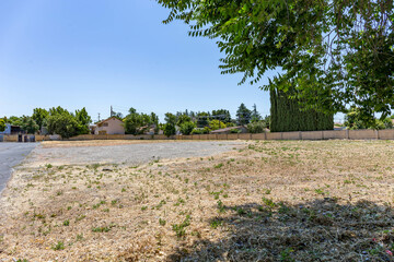 Vacant lot in a suburban Antioch, California neighborhood on a sunny day. The dry land and sparse grass suggest development potential or urban infill opportunity near residential housing.