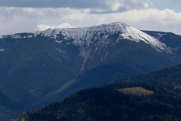 Zoomed-in view of a single Carpathian peak covered with spring snow under overcast skies. Ideal for...