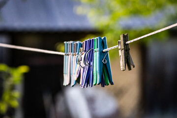 Close-up of colorful plastic and wooden clothespins hanging on a clothesline in a backyard, with a...