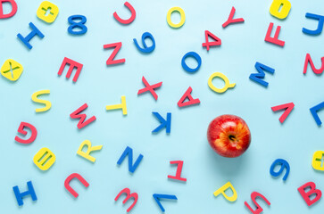 Colorful alphabet letters and a red apple on a light blue background. Back to school concept. 