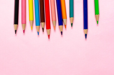 Collection of colorful sharpened pencils on a pink background with copy space.